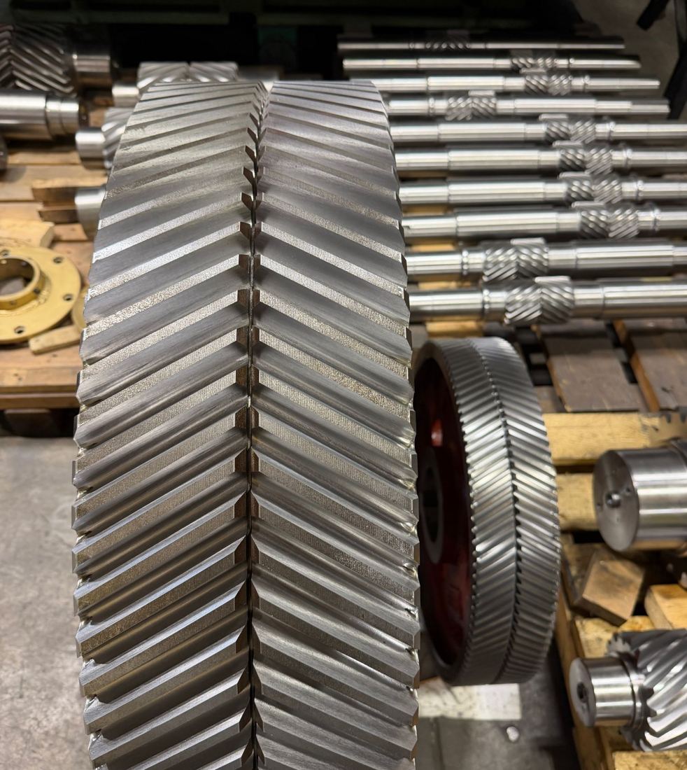 Large double-helical herringbone gear with a rack of helical pinion shafts behind it